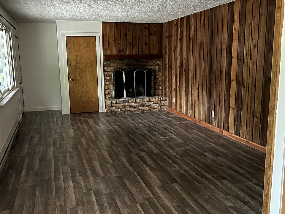 Spacious living area with a closet, modern laminate flooring, and two large windows