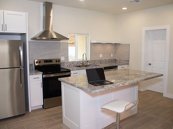 Open kitchen space leading to living room with brand new stainless steel appliances and huge kitchen island.