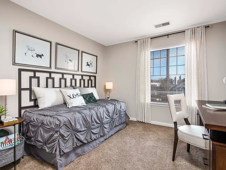 Furnished model bedroom with office desk and golf course view from the oversized bay windows