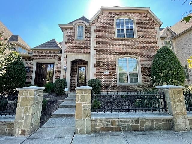 French country home with brick siding and a fenced front yard