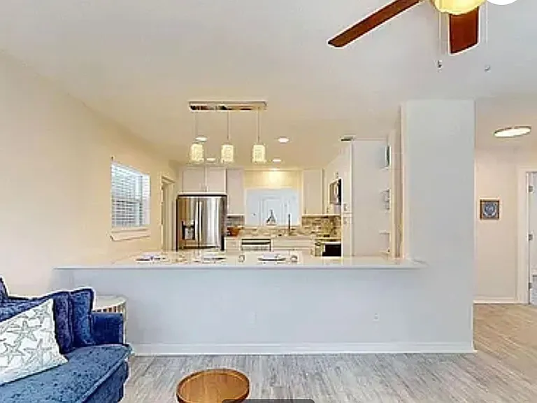 Kitchen peninsula with bar top seating area, pendant lighting, and open view into the living room