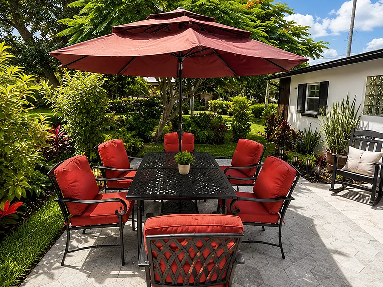 Relaxing outdoor seating surrounded by lush landscaping, palm trees, flowering plants, and a peaceful Old Florida atmosphere, minutes from the beach.