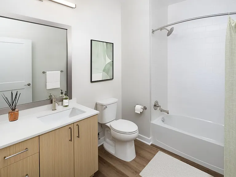 Upgrade Collection I bath with white quartz countertop, light oak cabinetry, and hard surface flooring