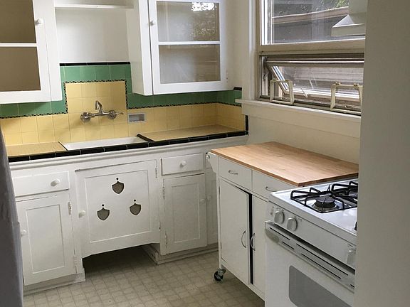 Vintage 1928 kitchen with moveable storage cutting board unit. Gas stove.