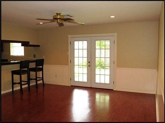 Family room has two tone paint with wainscotting, ceiling fan, recessed can flighting and laminate wood floors.