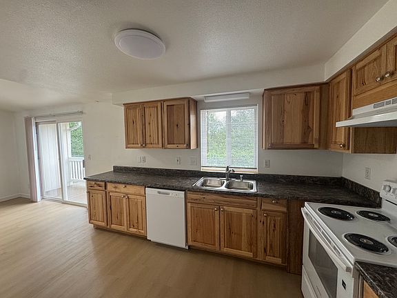 Open kitchen and dining area featuring ample cabinetry, full-size appliances, and easy access to the private deck for indoor-outdoor living.