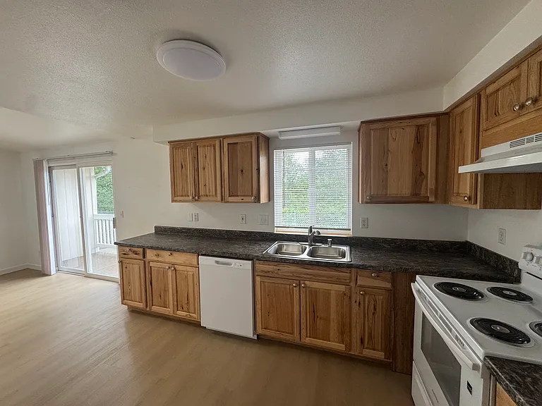 Open kitchen and dining area featuring ample cabinetry, full-size appliances, and easy access to the private deck for indoor-outdoor living.