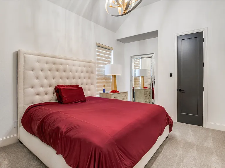Vaulted ceiling with an overhead light fixture, light gray carpet, and a dark paneled door with black hardware