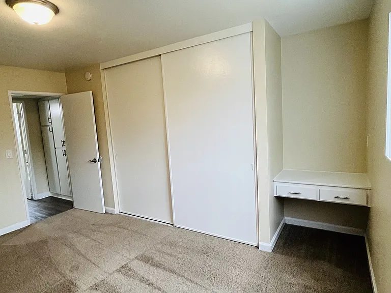 Carpeted bedroom with large closet and build in desk at Plaza Verde Apartments in Escondido, California.