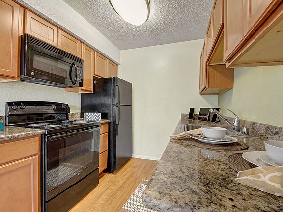 A kitchen with granite countertops, cabinet storage, and sleek black appliances