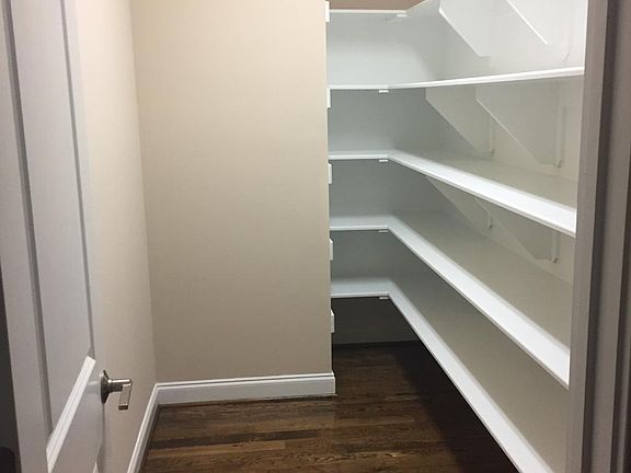 Walk in kitchen pantry with wooden shelves