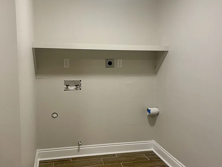 Spacious laundry room with connections for both electric and gas dryers, plus plenty of shelving for extra storage (not pictured).