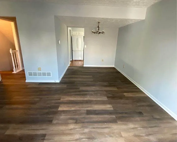 Seen here from the back door in the living room, the dining room (under the chandelier) and beyond that, the kitchen. To the left is the hallway to the stairs, and the powder room.