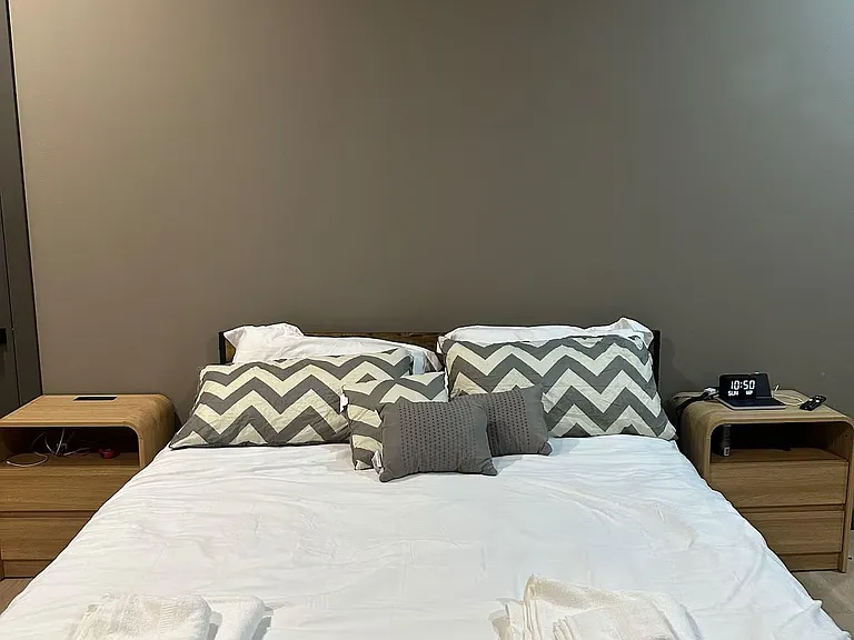 Furnished bedroom with a full/queen bed, matching nightstands, and convenient bedside outlets and lighting.