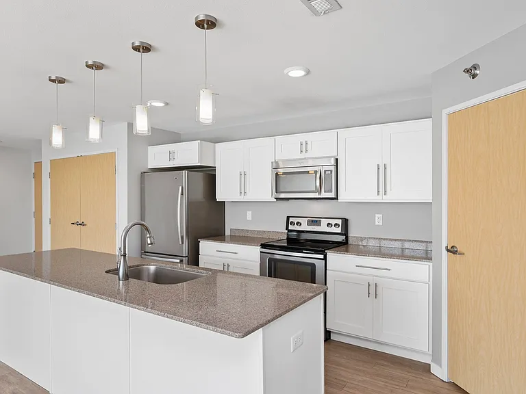 Modern kitchen with a sleek breakfast bar, stainless steel appliances, and elegant pendant lighting. Modern kitchen with a sleek breakfast bar, stainless steel appliances, and elegant pendant lighting.