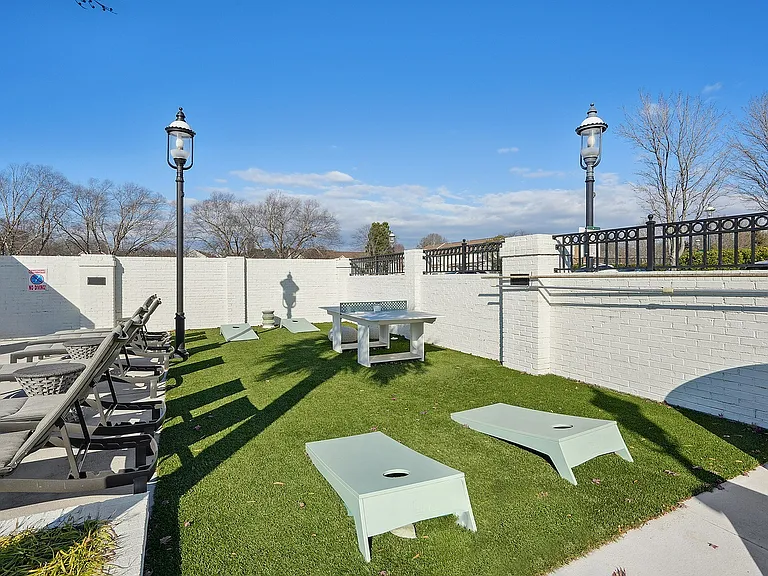 Outdoor leisure space featuring sun loungers, a picnic table, and a cornhole game area
