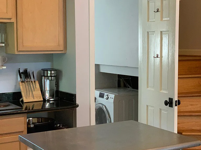 European style washer dryer combo unit is located under the stairs along with extra store space.