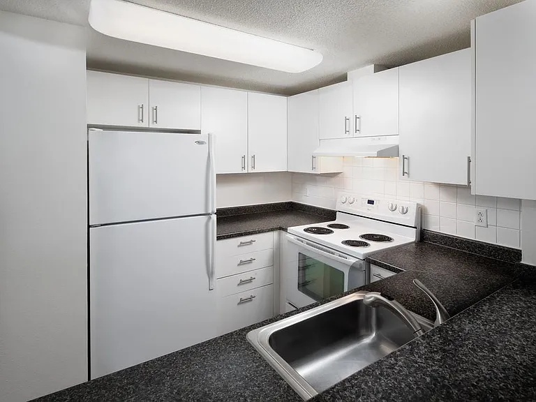 Classic Package I kitchen with white cabinetry, white tile backsplash, dark grey laminate countertops, white appliances, and hard surface flooring