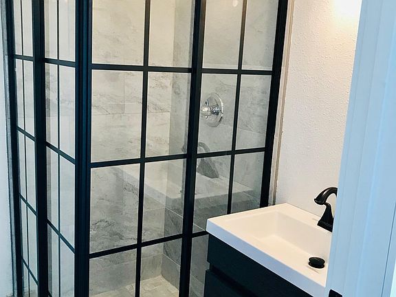 Bathroom with sliding glass surround shower, vanity, and washer/dryer.