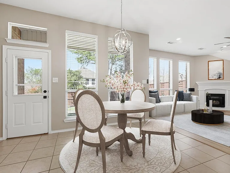 Open-concept dining and living area featuring neutral-toned walls, tile flooring, multiple windows with blinds, a modern ceiling fan, and a fireplace with a white mantel