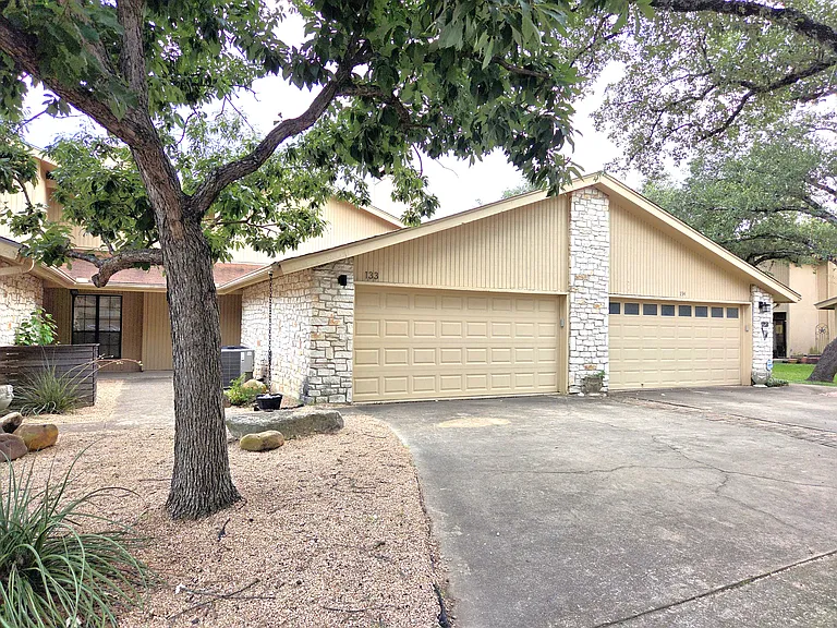 Front of townhome with attached 2 car garage and large shaded trees