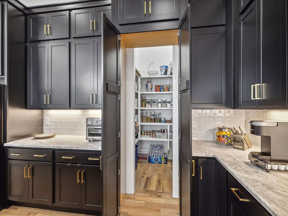 Hidden behind a facade of cabinets is a deep walk in pantry for food storage and hidden appliances such as a microwave.