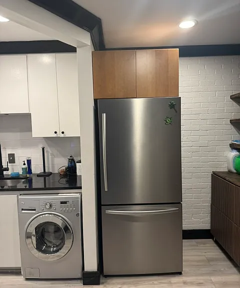 Kitchen space with refrigerator and washer/dryer unit. Extra storage above the refrigerator.