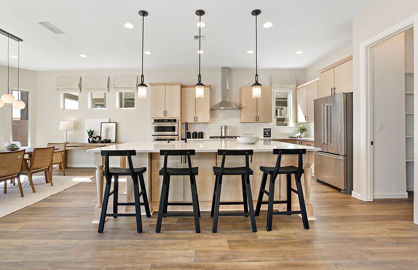 Spacious kitchen features a large, extended island with accent lighting fixtures to enjoy your morni