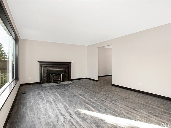 From the front door looking into the living room. Beautiful laminate flooring, wood burning stove insert, full wrap windows. Opening leads to dining area