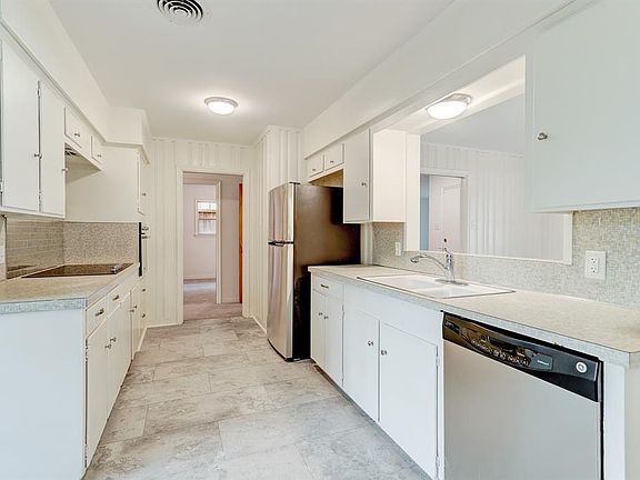 Cheerful Kitchen with updated appliances including stainless steel dishwasher and Refrigerator. Freshly painted cabinets with brushed nickel hardware. New lighting. Kitchen opens to dining area.