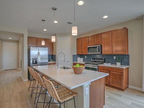 The Hewitt kitchen with stainless steel appliances, a quartz kitchen island and a large corner pantr