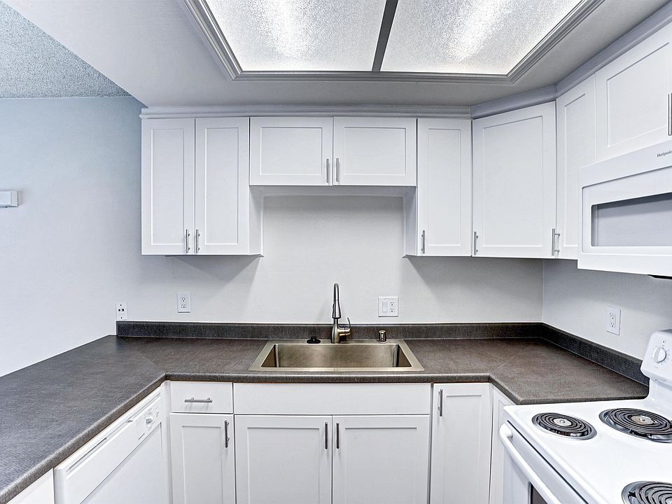 A kitchen with white cabinets and a stove top oven.