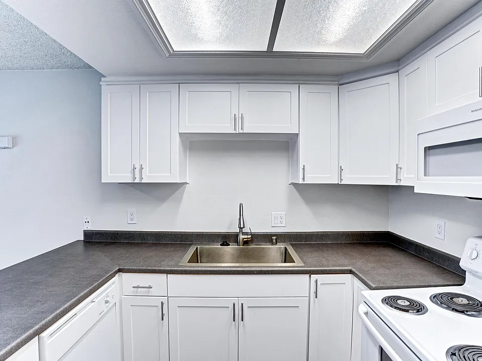 A kitchen with white cabinets and a stove top oven.
