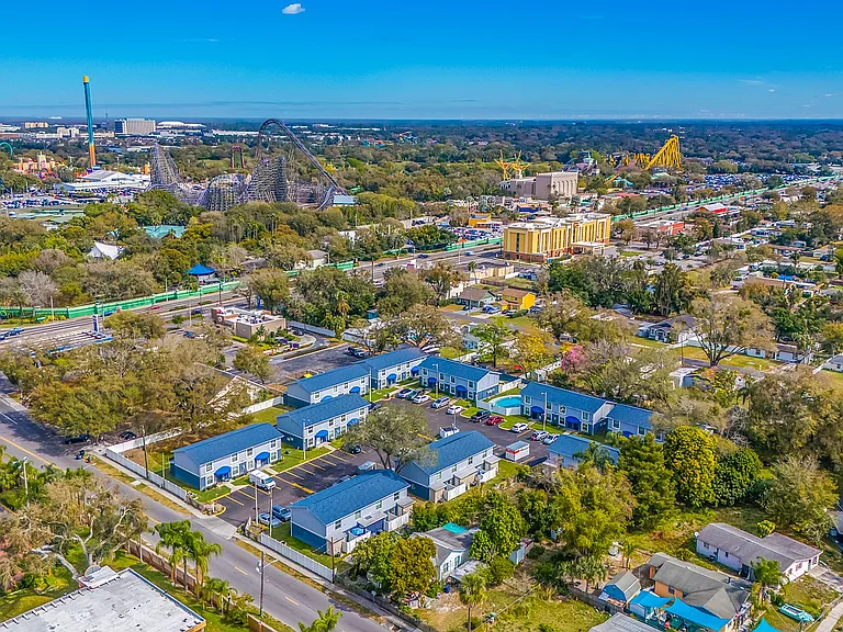Vibrant aerial view of a lively neighborhood featuring colorful buildings, lush greenery, and a thrilling amusement park nearby.