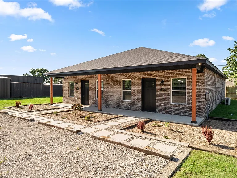 Brick exterior featuring a covered porch with natural wood-tone columns