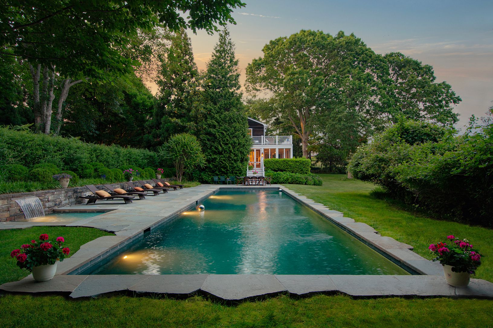 60-foot lap pool, waterfall spa, and patio at dusk