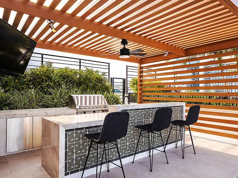 Griffis West Palm apartments rooftop deck with gazebo, BBQ grill, TV, and dining bar.