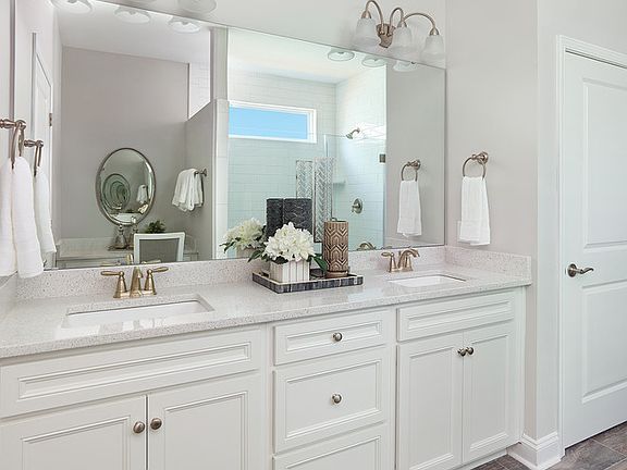 Owner s bath appointed with white cabinets, double sink and quartz countertops along with a frameles