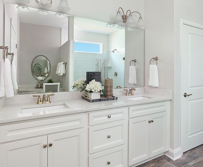 Owner s bath appointed with white cabinets, double sink and quartz countertops along with a frameles