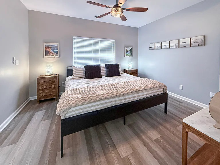 Primary King bedroom downstairs measures 11 x 13 with plush linens and modern coastal decor