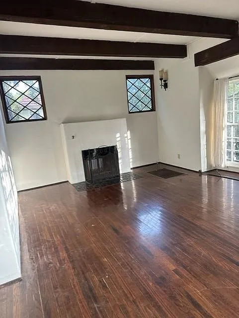 Good sized, charming living room with diamond windows, heavy wood, being ceilings, and woodburning fireplace!