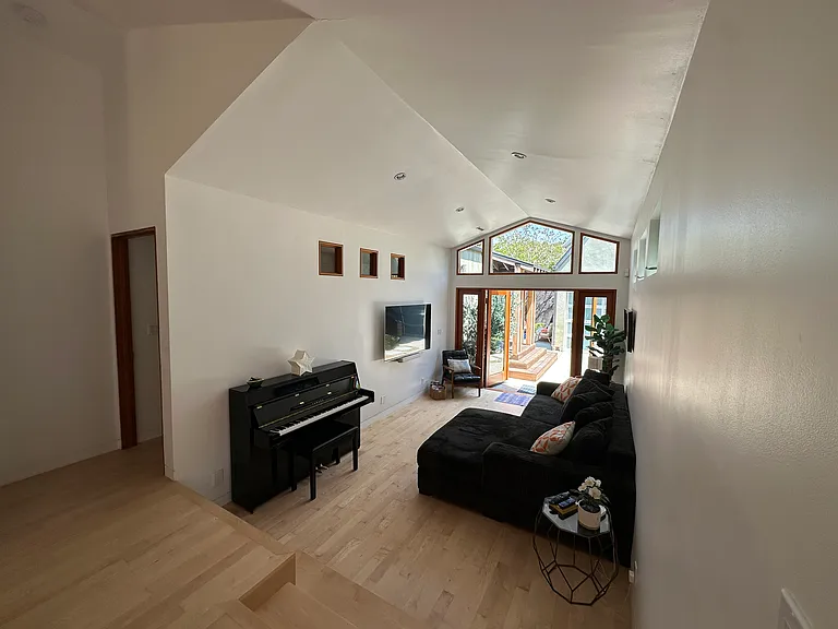Open plan high ceiling living area with piano, 60" screen, Sonos, etc - french doors to backyard