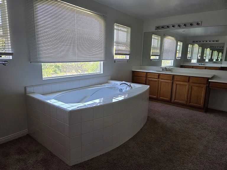 Master bathroom with large bathtub and individual sinks on each side of the room.