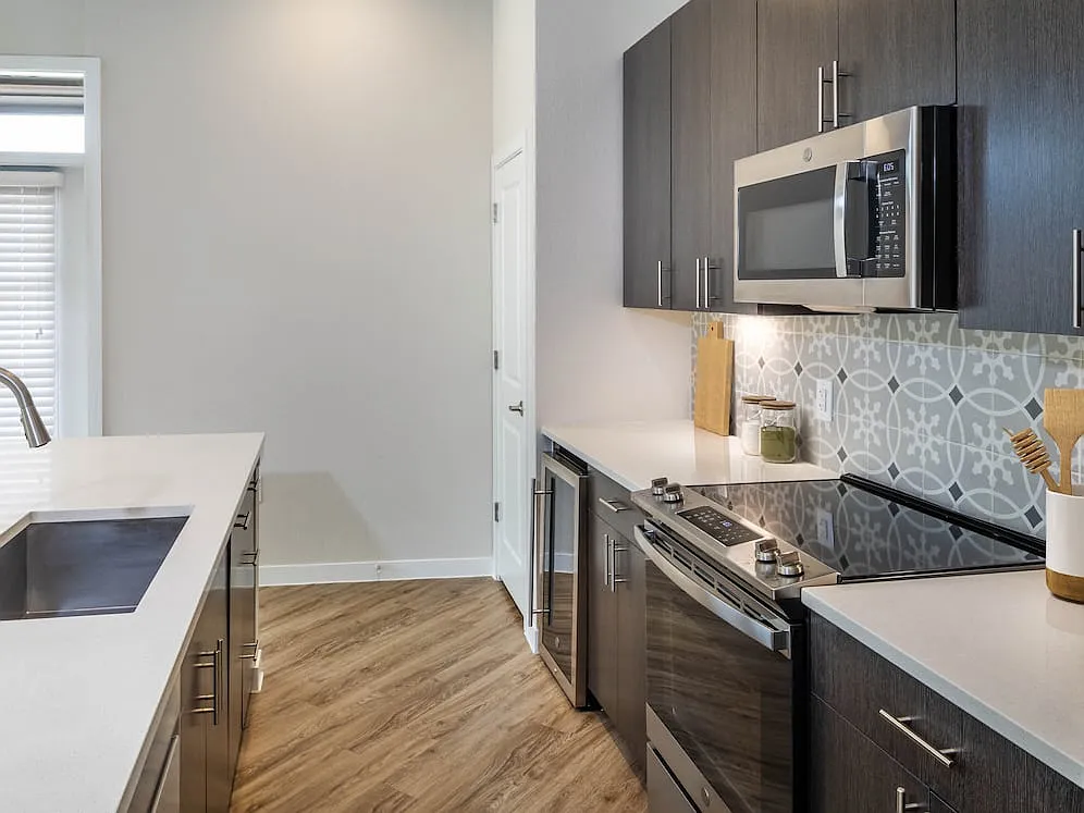 Kitchens with stainless steel appliances, wine fridges, quartz countertops, tile backsplash, and hard surface flooring - Avalon Townhome Collection Bee Cave