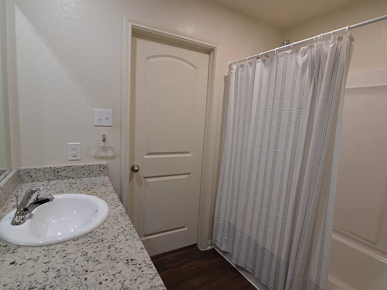 Well-maintained bathroom featuring granite vanity, modern fixtures, and full tub/shower combination.