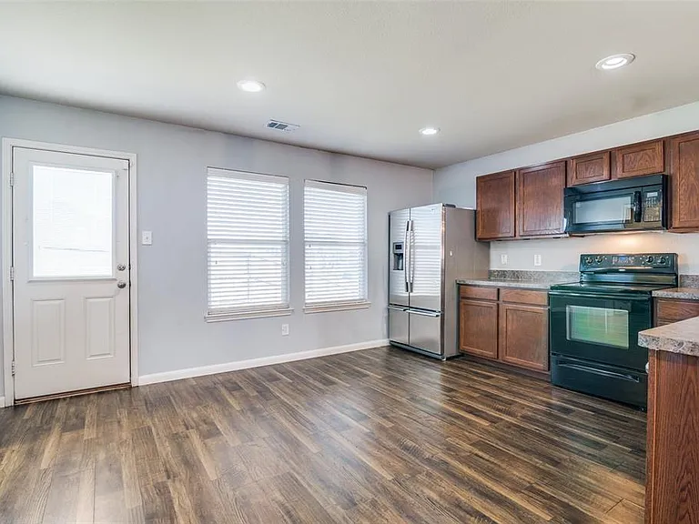 Kitchen with dark wood-type flooring, black appliances, and plenty of natural light