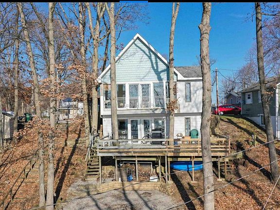 Back of home showing large windows with beautiful views of Lake Freeman and three sitting areas, two decks and a patio with a fire pit.
