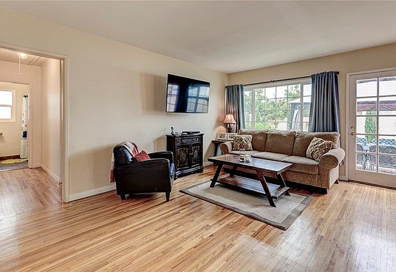 Open living room w/wood floors and door leading to backyard