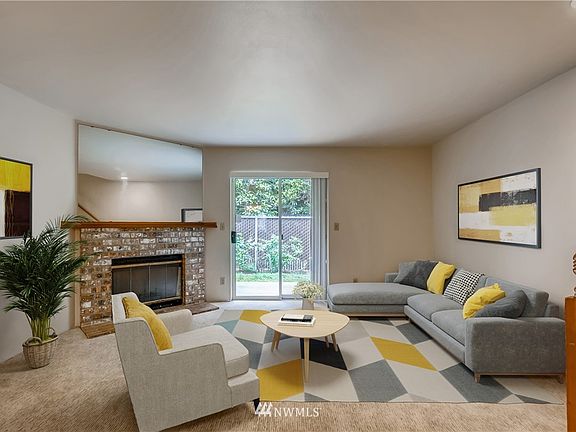 Spacious living room with new carpet (throughout home), wood-burning fireplace (save on winter heating) and private view onto patio & garden space!