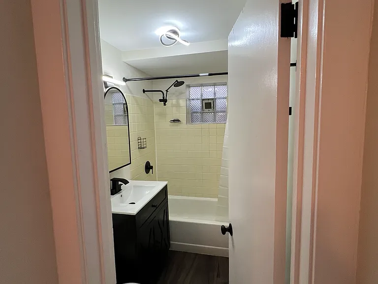 view of the bathroom from the entryway - bathroom is newly updated with finishes, new vanity, flooring, and mirror as well as shower